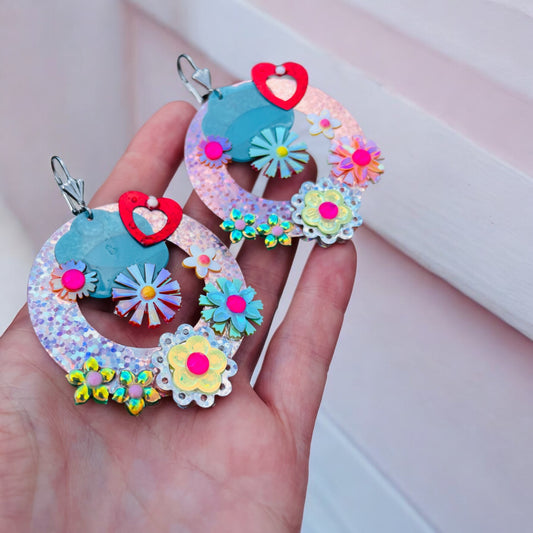 Vue de côté des boucles d'oreilles en résine avec motifs floraux et sequins