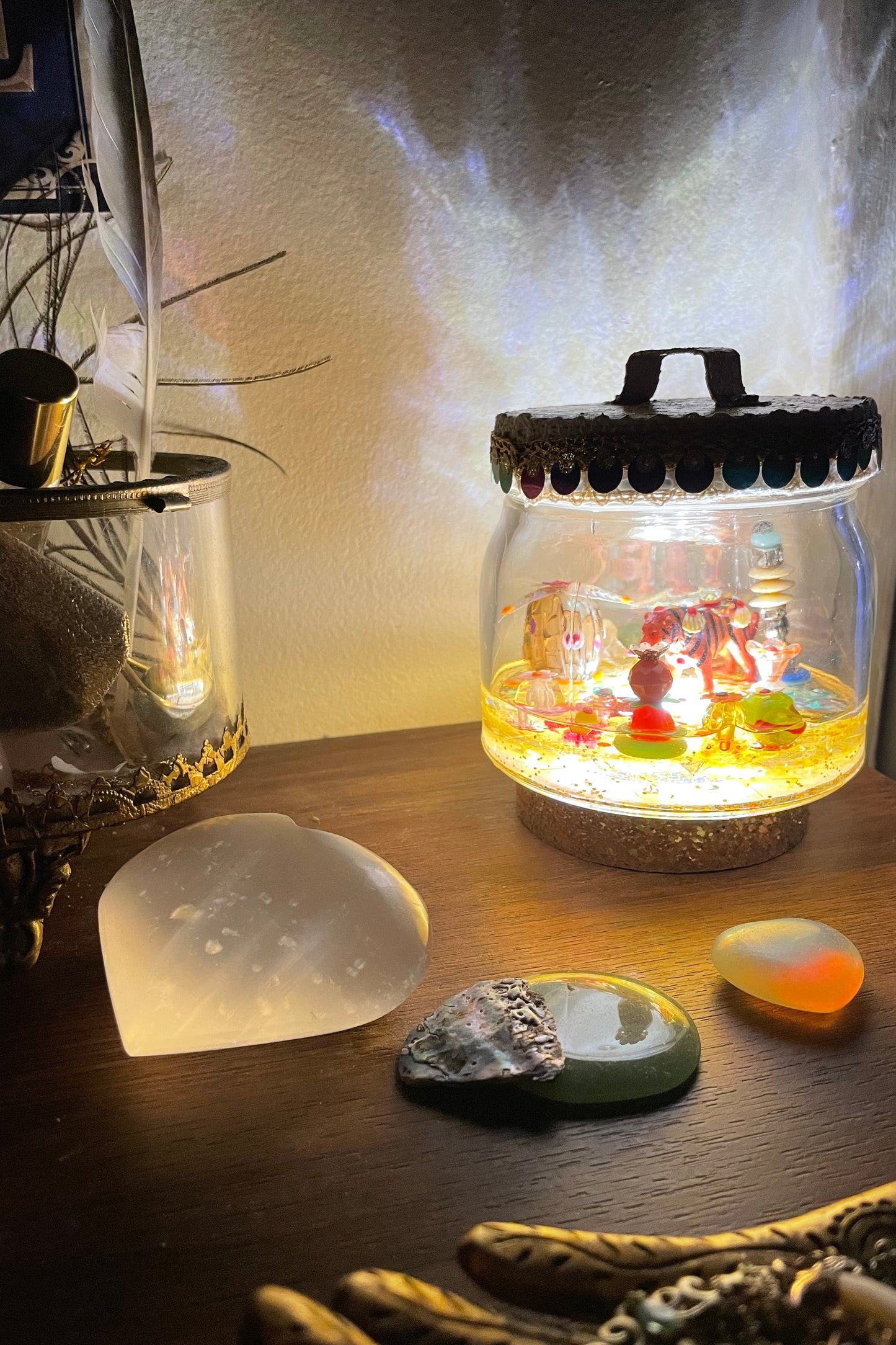 Veilleuse à poser en résine avec jardin imaginaire et animaux totems allumée sur une commode dans une chambre